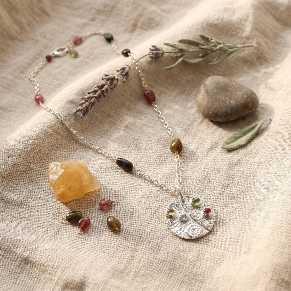 Necklace with gemstones and a stone pendant on a textured fabric background