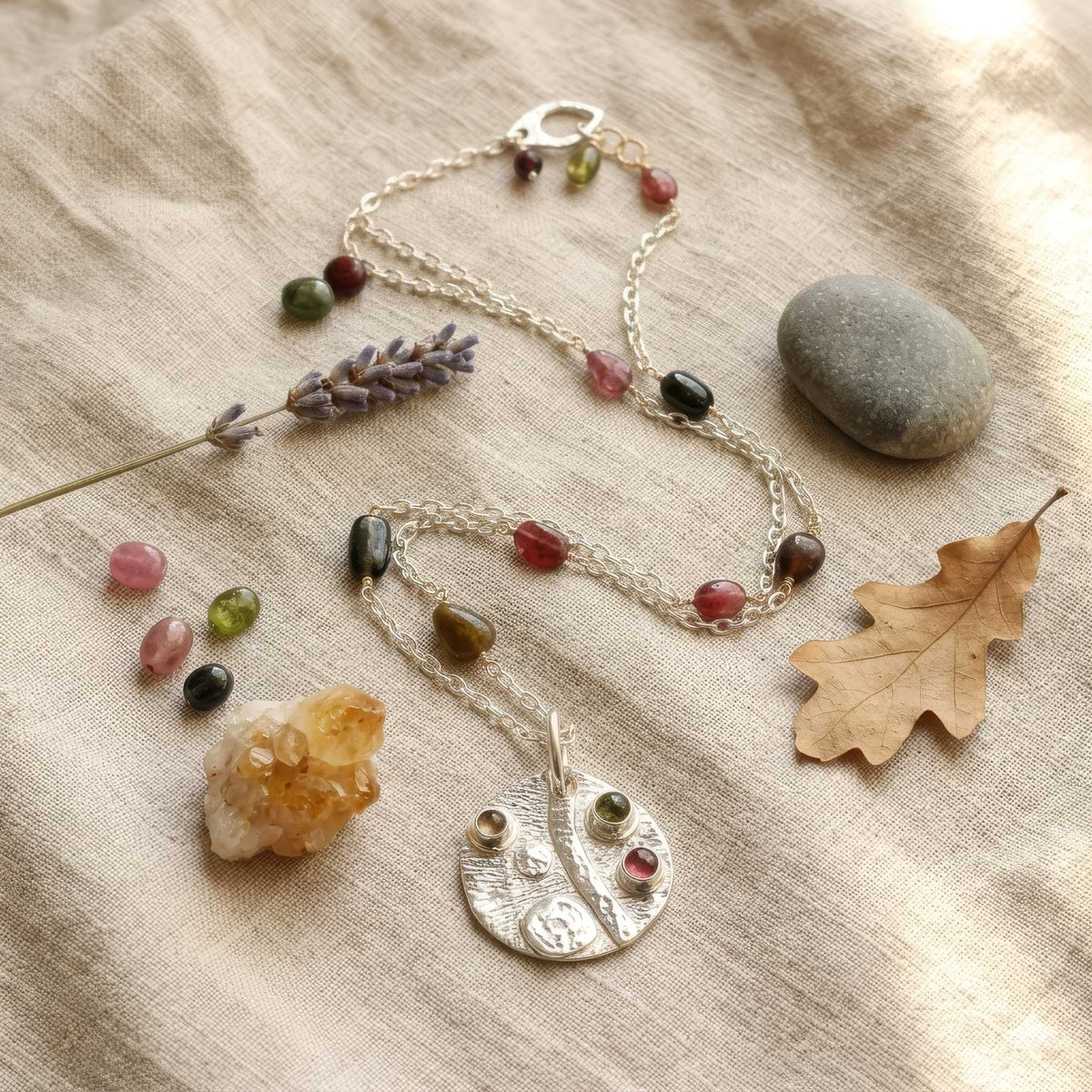gemstone necklace on linen with props around it