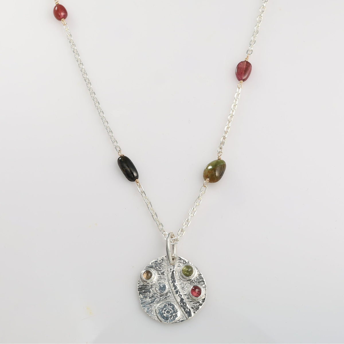Necklace with a silver pendant and multicolored beads on a white background