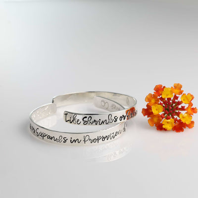 Anaïs Nin courage quote cuff bracelets in Argentium silver by Breathe Autumn Rain with orange flower on white background