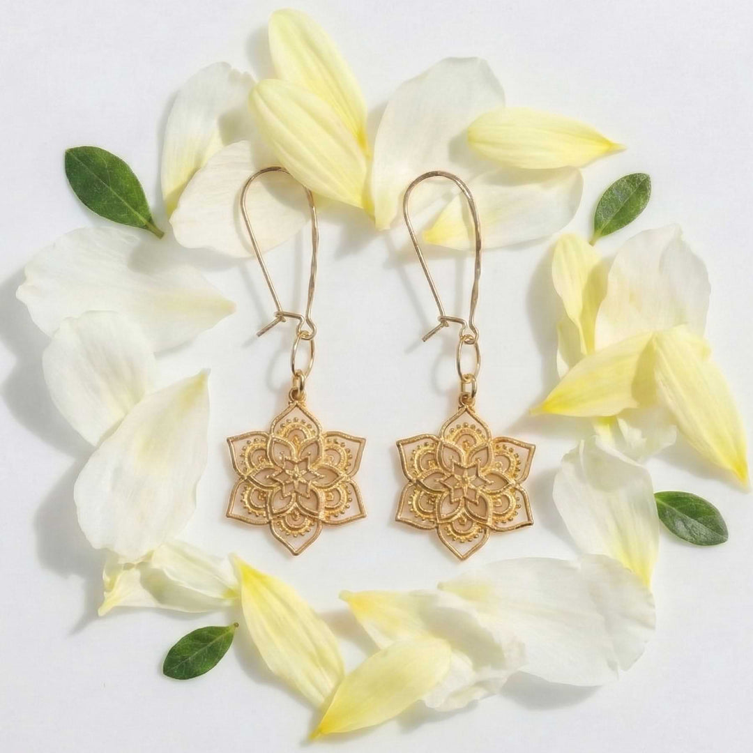 Golden mandala earrings arranged in a circle of soft yellow flower petals, highlighting the openwork design.