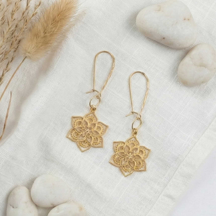 24k gold vermeil mandala earrings resting on white natural stones and linen fabric with dried pampas grass.