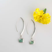 Alt image of Minimalist silver drop earrings with long sculptural hooks featuring bezel-set green tourmaline cabochons.