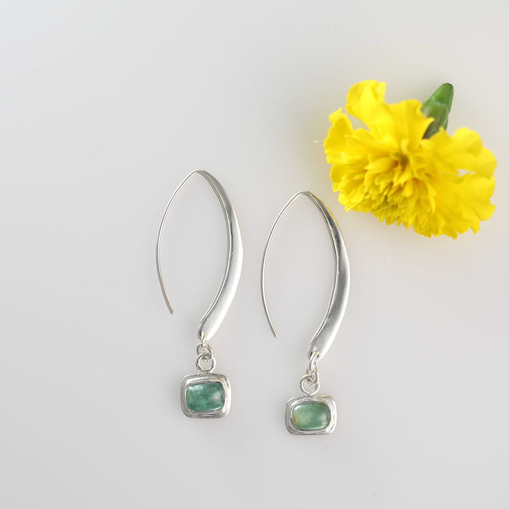Alt image of Minimalist silver drop earrings with long sculptural hooks featuring bezel-set green tourmaline cabochons.