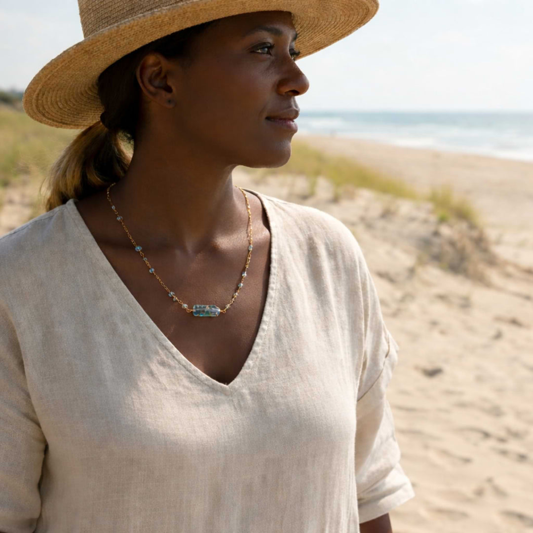 Woman wearing the Helena Aquamarine Bar Necklace showing how the dainty blue beads sit against the skin for a subtle, elegant look.