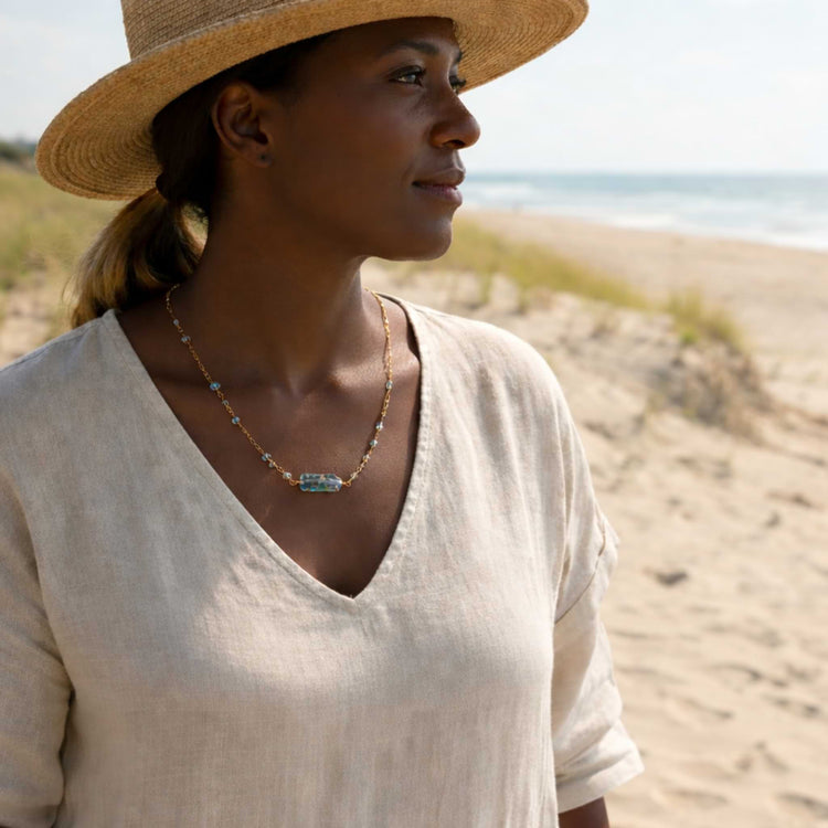 Woman wearing the Helena Aquamarine Bar Necklace showing how the dainty blue beads sit against the skin for a subtle, elegant look.