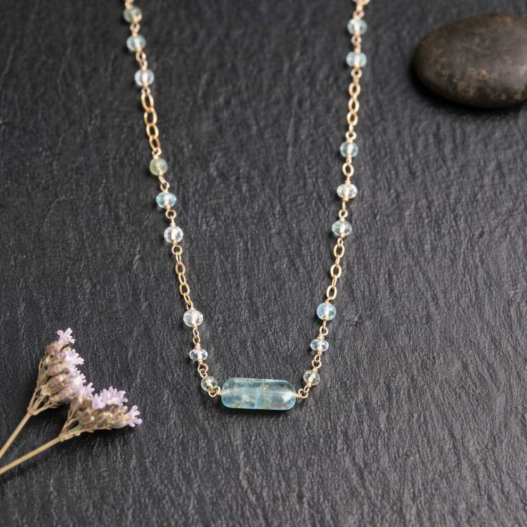 Close-up macro shot of the faceted aquamarine beads and the organic aquamarine nugget bar showing the gold wire wrapping details.