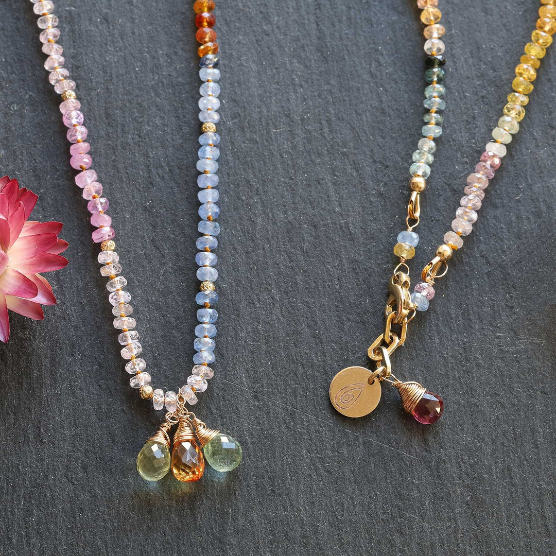 close-up of sapphire beads and gold accents on 14k gold necklace, styled with natural textures