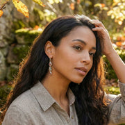 Life-style picture of linear drop earrings featuring rose-cut pink, orange, and green sapphires set in sterling silver.