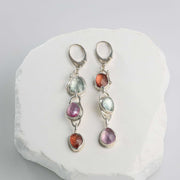 Three-tier linear drop earrings featuring rose-cut pink, orange, and green sapphires set in sterling silver.