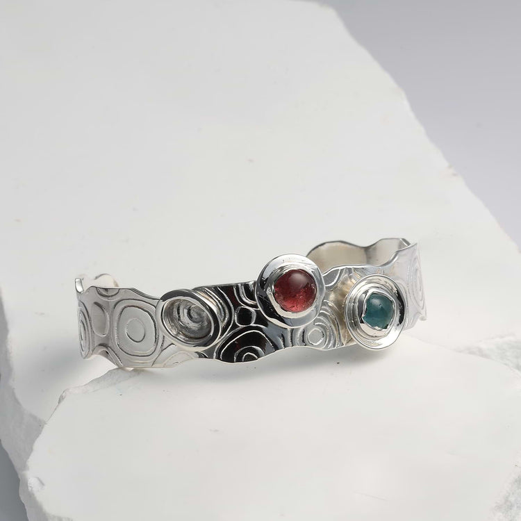 Textured Argentium silver cuff bracelet featuring retro swirl patterns and bezel-set multi-color tourmalines.