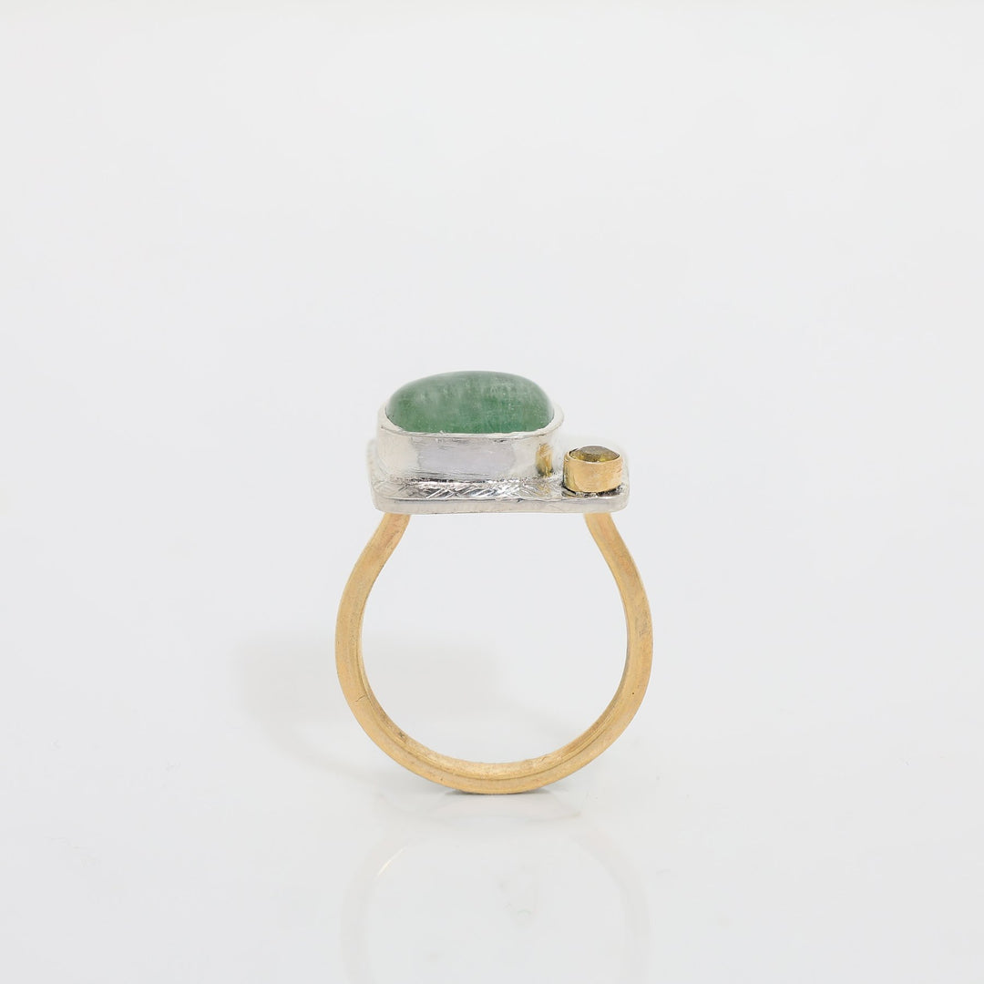 Ring with green stone and gold accents on a white background