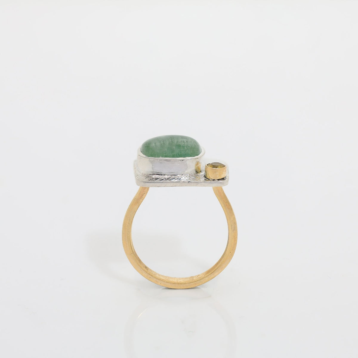 Ring with green stone and gold accents on a white background