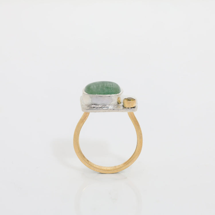 Ring with green stone and gold accents on a white background