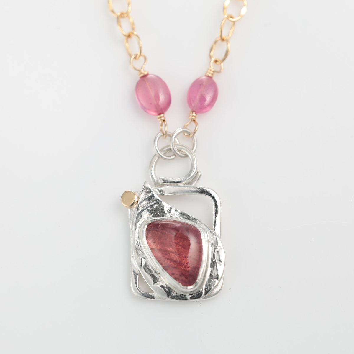 Necklace with pink beads and a silver pendant on a white background