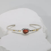 Fiery red sapphire cuff bracelet with warm gold fused onto textured Argentium silver.
