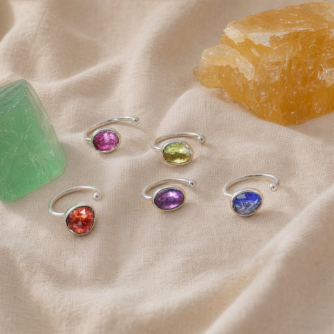 Set of silver rings with colorful gemstones on a beige fabric background