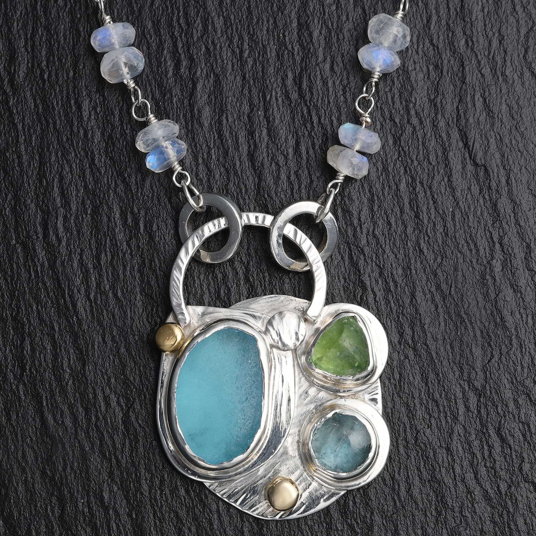 Close up of textured Argentium silver pendant with 18k gold accents and bezel-set sea glass and gemstones.